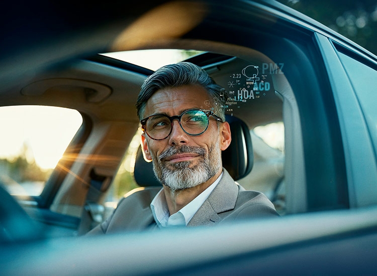 Mann mit Brille und Datenstrahl sitzt im Auto und schaut aus dem Fenster 