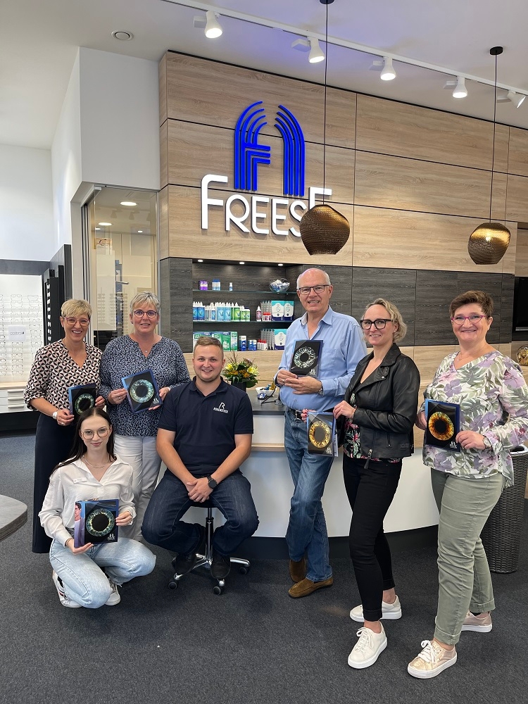 Das Team von Optik Freese hält Fotos von Iris-Scans in der Hand 